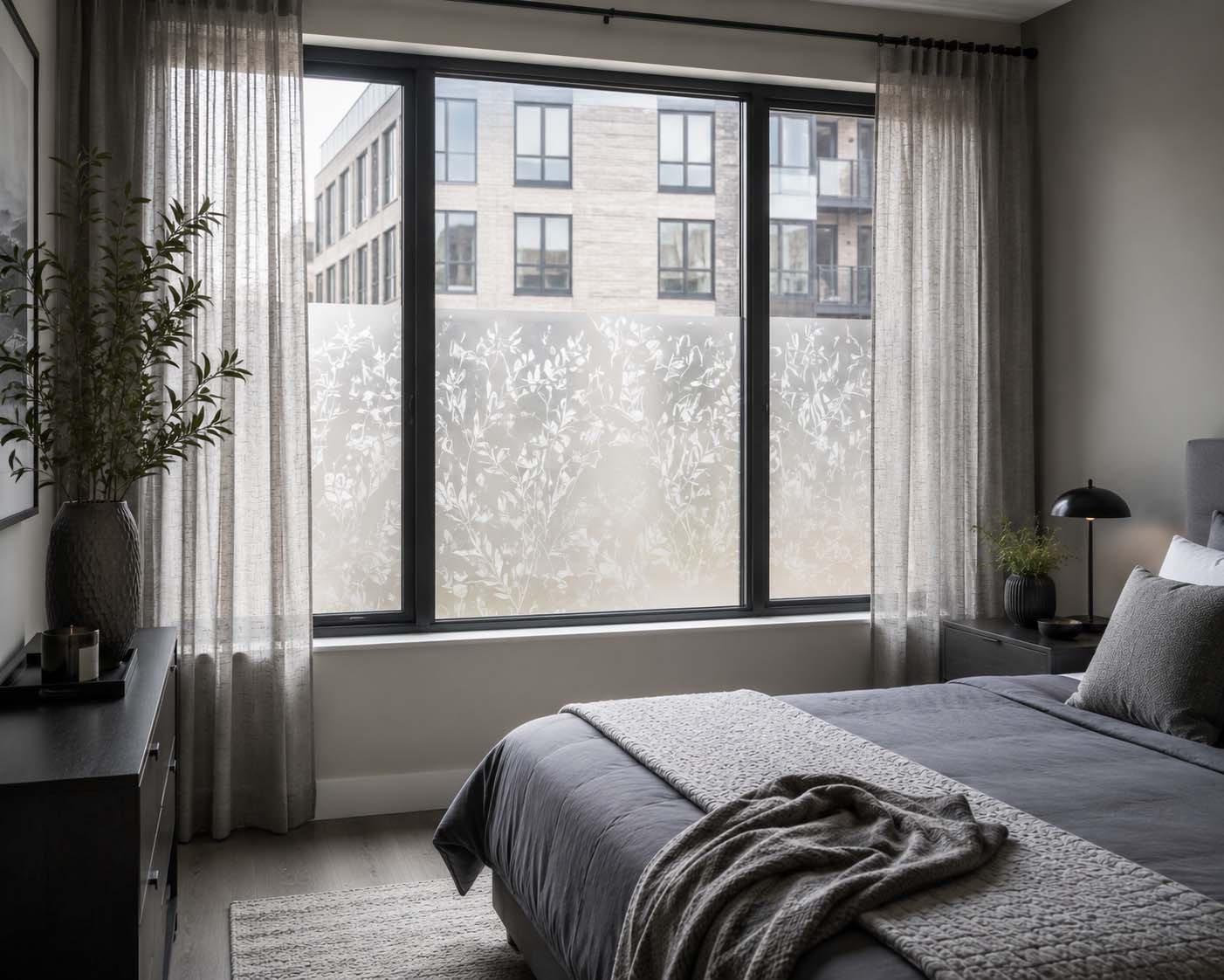 Window privacy film softening an ugly view in a modern gray bedroom while allowing natural light to brighten the space.