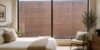 How to fix an ugly view in a bedroom with a large picture window overlooking a plain brick wall, showing how an unattractive view can affect an otherwise beautiful space.