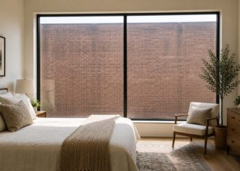How to fix an ugly view in a bedroom with a large picture window overlooking a plain brick wall, showing how an unattractive view can affect an otherwise beautiful space.